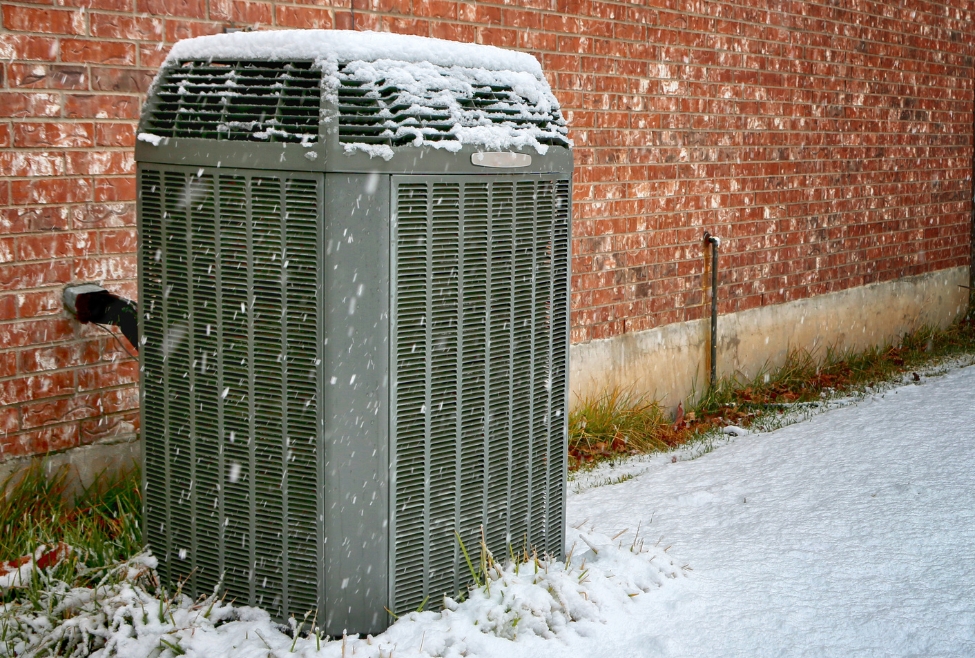 Outdoor air conditioning unit covered in snow, highlighting the importance of winterizing AC units. Are you wondering whether ac units need to be winterized? Ensure peak performance with professional AC maintenance near me. Professional electrician and HVAC technician near me. Contact us to schedule an appointment for ac maintenance near me in Coeur d'Alene, CDA, Post Falls, Hayden, Rathdrum, Sandpoint, Spirit Lake, St Maries, Athol, Blanchard, Dalton Gardens, Worley, Plummer, or Harrison, ID. Expert assistance for ac repair, maintenance and installation. Contact J.A. Bertsch Heating and Cooling today for cooling system maintenance!
