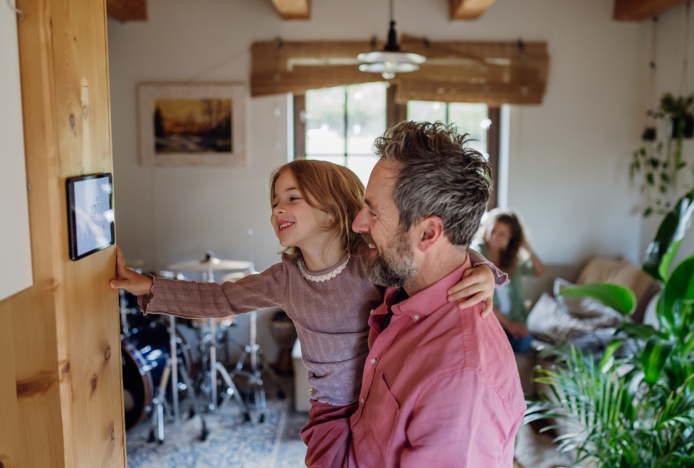 Young girl assisting her father to adjust the heating temperature on a smart thermostat, symbolizing the benefits of upgrading to smart technology for efficient home heating. Illustrates the concept of sustainable and smart home heating solutions. Keywords: smart thermostat, sustainable technology, efficient heating, home heating, thermostat services, thermostat upgrade near me, thermostat installation near me, thermostat maintenance near me, thermostat repair near me, J.A. Bertsch Heating and Cooling. Service areas: Coeur d'Alene, CDA, Post Falls, Hayden, Rathdrum, Sandpoint, Spirit Lake, St Maries, Athol, Blanchard, Dalton Gardens, Worley, Plummer, and Harrison, ID.
