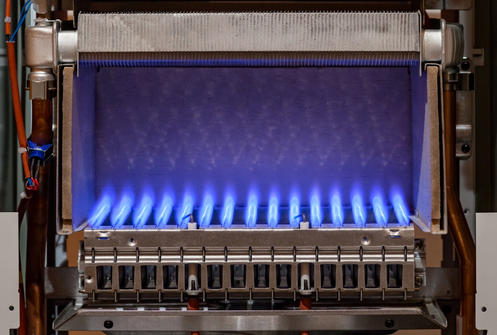 Gas water heater furnace with visible flames inside, illustrating the process of how to light a pilot light. Learn expert tips and solutions from J.A. Bertsch Heating, Cooling & Electrical, serving Coeur d'Alene, Hayden, and surrounding areas with professional heating and furnace repair services. Call today for help with how to light a pilot light, pilot light troubleshooting, how to relight a furnace pilot light, gas furnace pilot light not working, pilot light won't stay lit, steps to light a pilot light, how to light a gas water heater pilot light, furnace pilot light out, how to tell if pilot light is out, gas water heater pilot light repair near me, heating repair services near me, furnace maintenance and repair, HVAC troubleshooting tips, gas furnace repair near me, furnace pilot light ignition issues, pilot light won't ignite, water heater pilot light out, how to fix a pilot light, heating and cooling services in Coeur d'Alene, furnace services in Hayden, reliable HVAC services near me, furnace repair professionals in Sandpoint, heating solutions in Rathdrum, gas furnace pilot light problems.